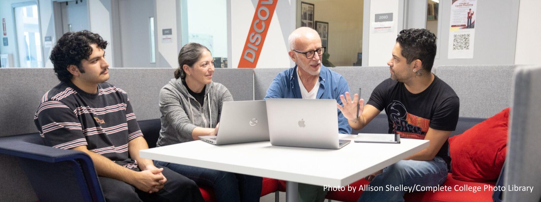 An image of a multiethnic group of faculty meeting in a common area on a college campus.